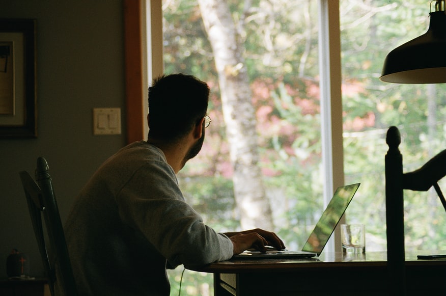 man in gray shirt looking out from his home